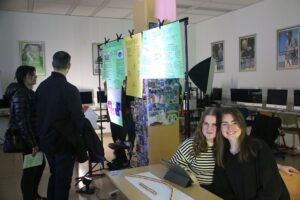 Schülerexpertinnen und Besucher während des Präsentationsabends am Stand zum Thema E-Mobilität 2 besucher